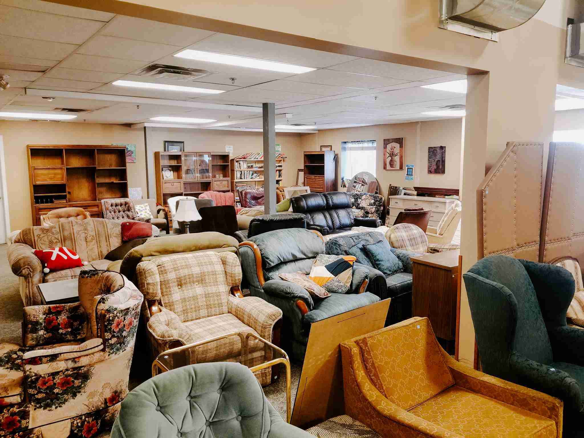 A variety of secondhand furniture on display at Habitat for Humanity ReStore in Regina, Saskatchewan. The space features vintage armchairs, couches, bookshelves, and home decor, offering unique thrifting opportunities for sustainable shopping and home improvement projects.